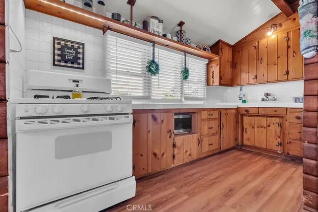 a kitchen with stainless steel appliances granite countertop a sink a stove and wooden floors