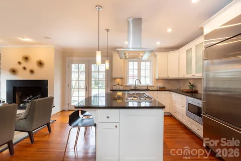 a kitchen with stainless steel appliances granite countertop a refrigerator a stove and a wooden floors