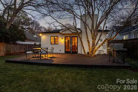 a view of a backyard with table and chairs potted plants and large tree