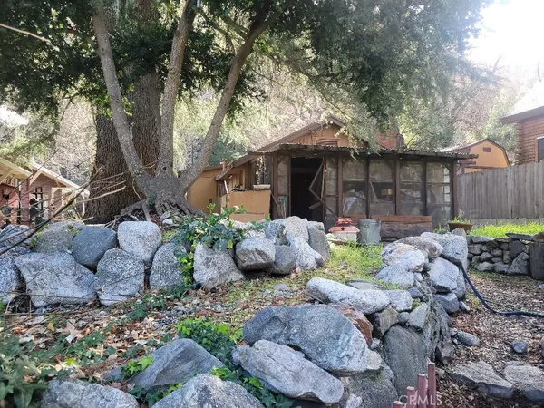 a view of a backyard with table and chairs potted plants and large tree