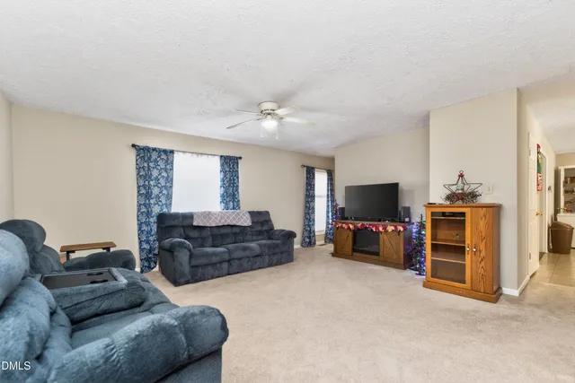 a living room with furniture a ceiling fan and a window