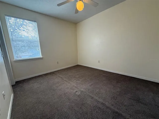 an empty room with a window and a fan