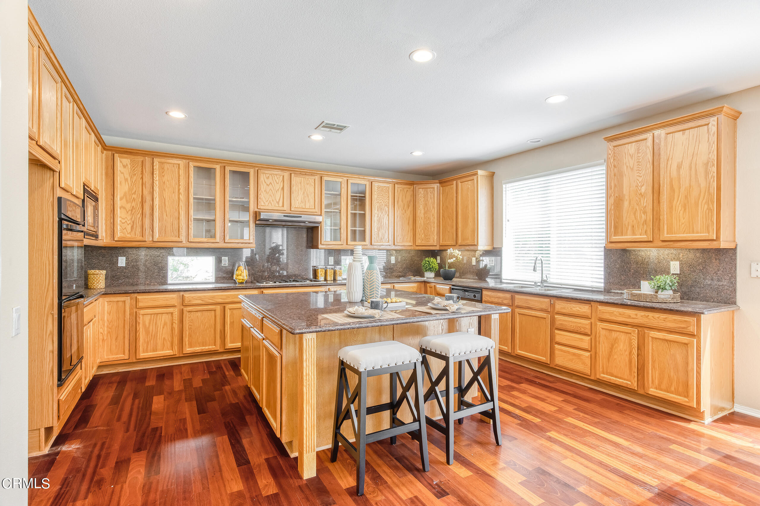 26569 Shakespeare Lane Stevenson Ranch, CA 91381 - Photo 16 of 55 a kitchen with stainless steel appliances granite countertop a stove top oven a sink dishwasher and cabinets with wooden floor