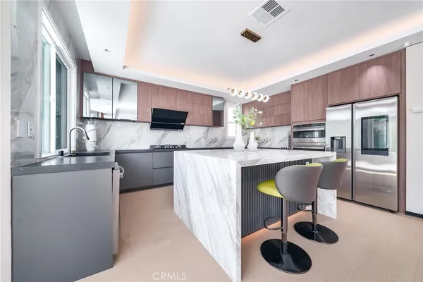 a kitchen with kitchen island stainless steel appliances a sink a counter top space cabinets and a window