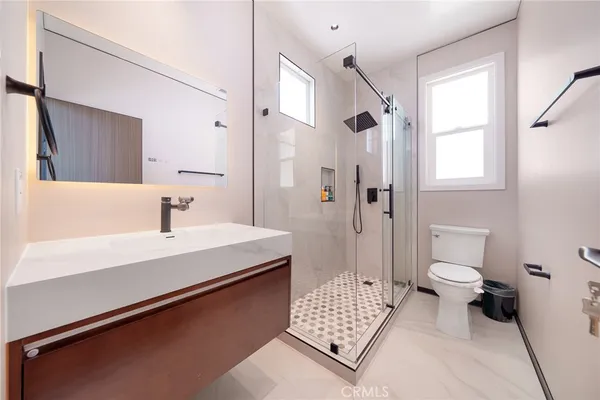 a bathroom with a sink a toilet a shower and a mirror