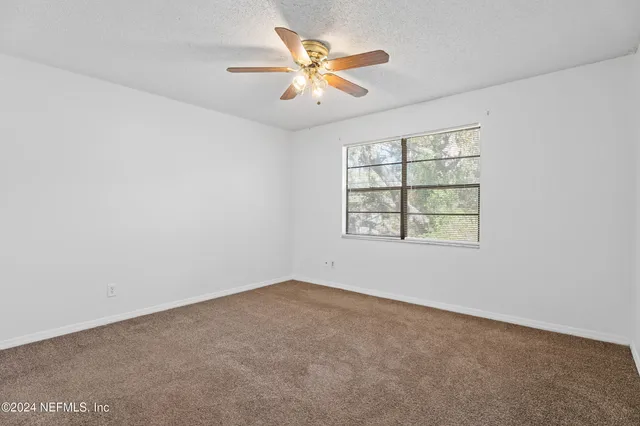 an empty room with windows and ceiling fan