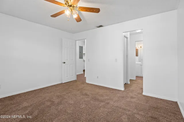 an empty room with closet and a chandelier fan