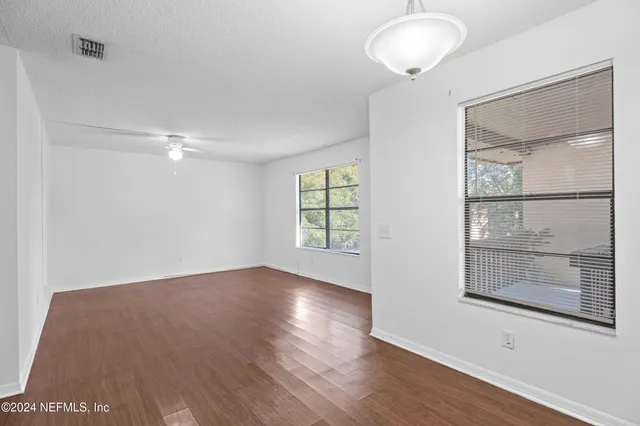 an empty room with wooden floor and windows