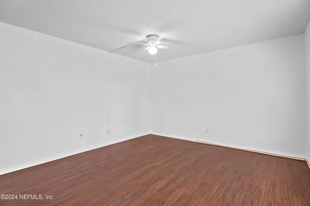 a view of a room with wooden floor and a ceiling fan