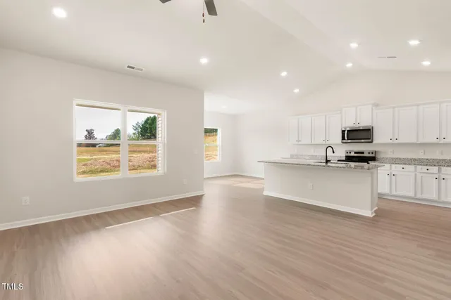 a view of kitchen with granite countertop stainless steel appliances stove sink and cabinets