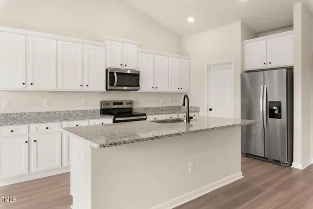 a kitchen with stainless steel appliances granite countertop a refrigerator sink and white cabinets