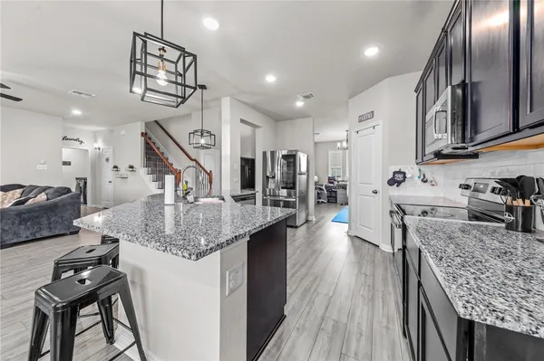 a kitchen with stainless steel appliances granite countertop a sink dishwasher a refrigerator and wooden floor
