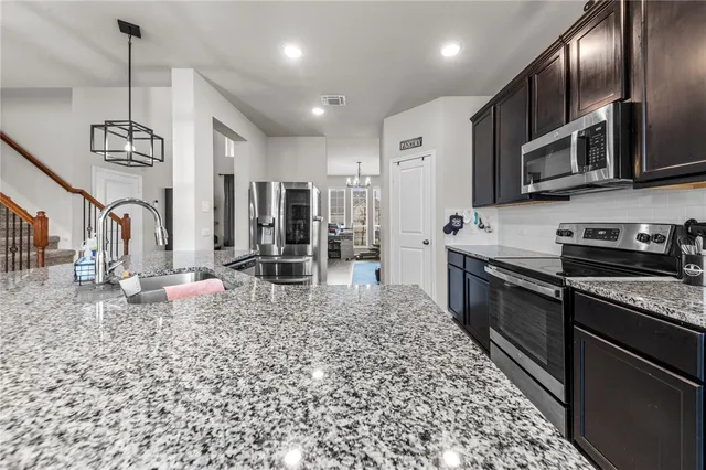 a kitchen with stainless steel appliances kitchen island granite countertop a refrigerator a stove and a sink with wooden floor