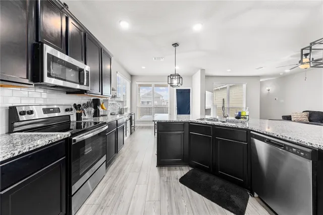 a kitchen with stainless steel appliances granite countertop sink stove and refrigerator