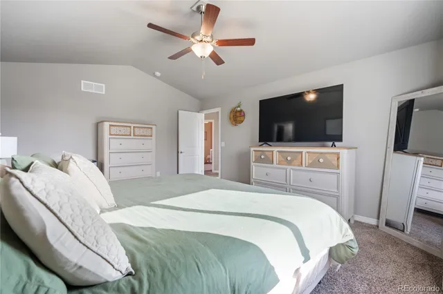 a bedroom with a bed a flat tv screen and a chandelier