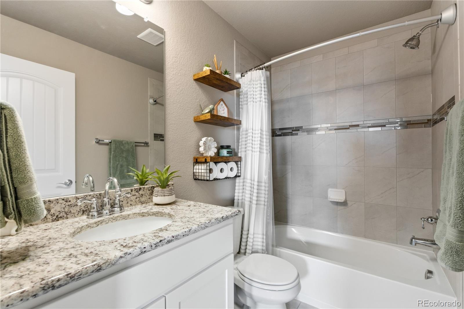 2173 Angus Street Mead, CO 80542 - Photo 19 of 28 a bathroom with a granite countertop sink a toilet and shower