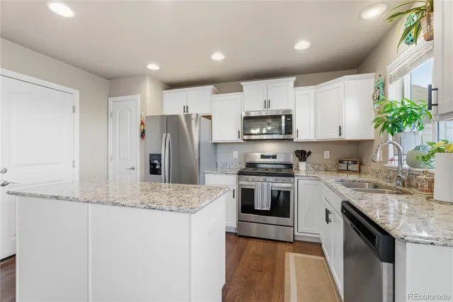 a kitchen with kitchen island granite countertop white cabinets and refrigerator