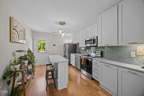 a kitchen with stainless steel appliances granite countertop a refrigerator a stove a sink dishwasher and white cabinets with wooden floor