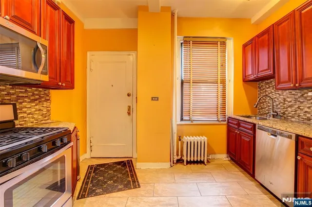 a kitchen with stainless steel appliances granite countertop a stove a sink and a microwave
