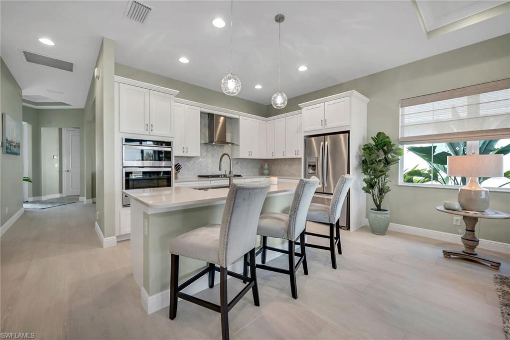 9020 Mayreau Way Naples, FL 34114 - Photo 4 of 28 a kitchen with kitchen island a refrigerator stove microwave and cabinets
