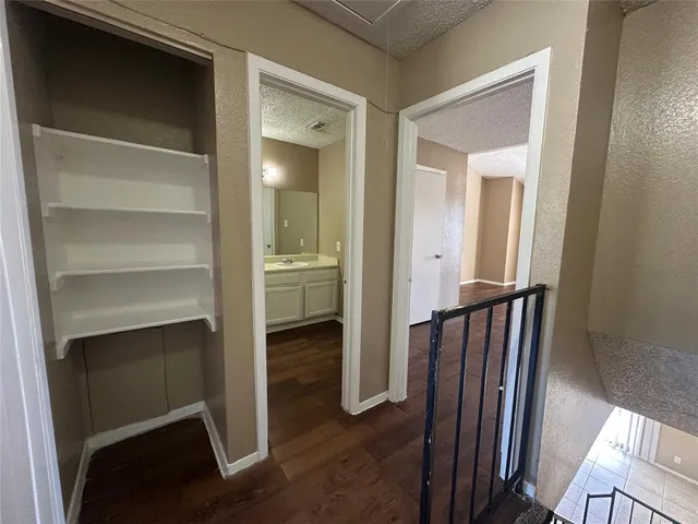a view of a hallway with wooden floor and a bathroom