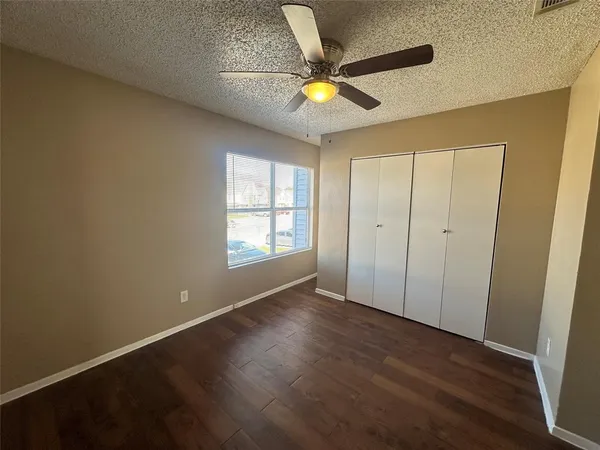 an empty room with wooden floor fan and windows