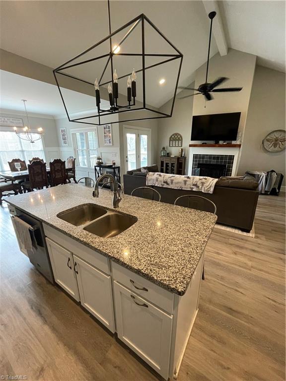 8805 Colgate Road Stokesdale, NC 27357 - Photo 34 of 34 View from kitchen with solid surface counter tops looking into the Great room with open floor plan, gas logs, vinyl plank flooring. Great for entertaining and opens to the covered back deck that looks over the large fenced in back yard with garden boxes and a cute chicken house.