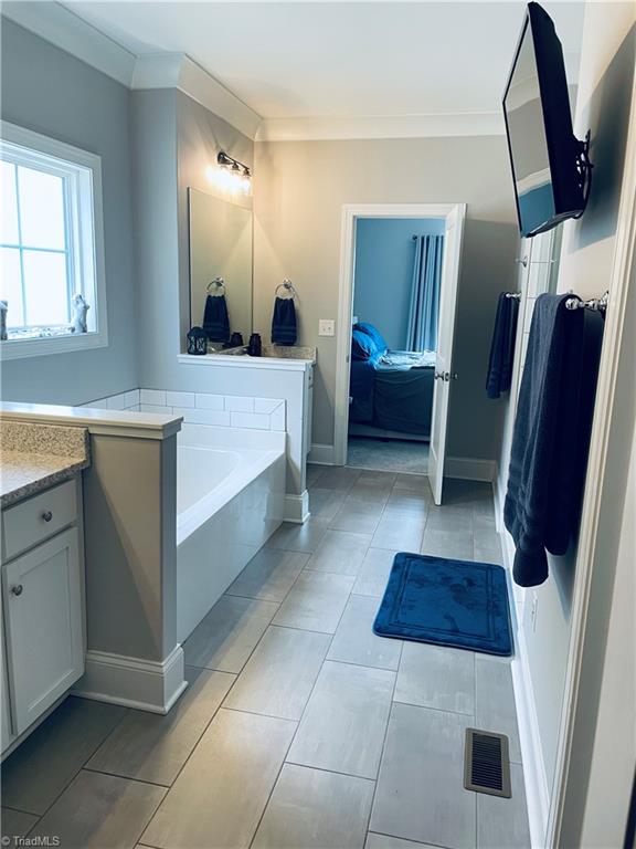 8805 Colgate Road Stokesdale, NC 27357 - Photo 9 of 34 Large bath just off the primary bedroom boast of space with tiled, separate shower, garden tub, two sink areas, TV and large walk in closet