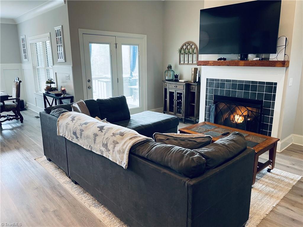 8805 Colgate Road Stokesdale, NC 27357 - Photo 28 of 34 Great room with open floor plan, gas logs, vinyl plank flooring. Great for entertaining and opens to the covered back deck that looks over the large fenced in back yard with garden boxes and a cute chicken house.