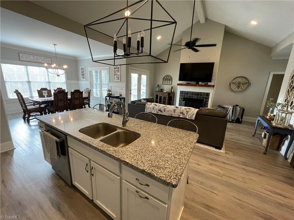 8805 Colgate Road Stokesdale, NC 27357 - Photo 30 of 34 View from kitchen with solid surface counter tops looking into the Great room with open floor plan, gas logs, vinyl plank flooring. Great for entertaining and opens to the covered back deck that looks over the large fenced in back yard with garden boxes and a cute chicken house.
