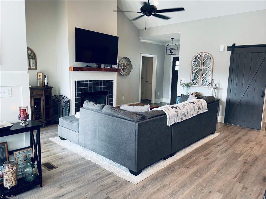 8805 Colgate Road Stokesdale, NC 27357 - Photo 32 of 34 View from dining area looking into the Great room with open floor plan, gas logs, vinyl plank flooring. Great for entertaining and opens to the covered back deck that looks over the large fenced in back yard with garden boxes and a cute chicken house.