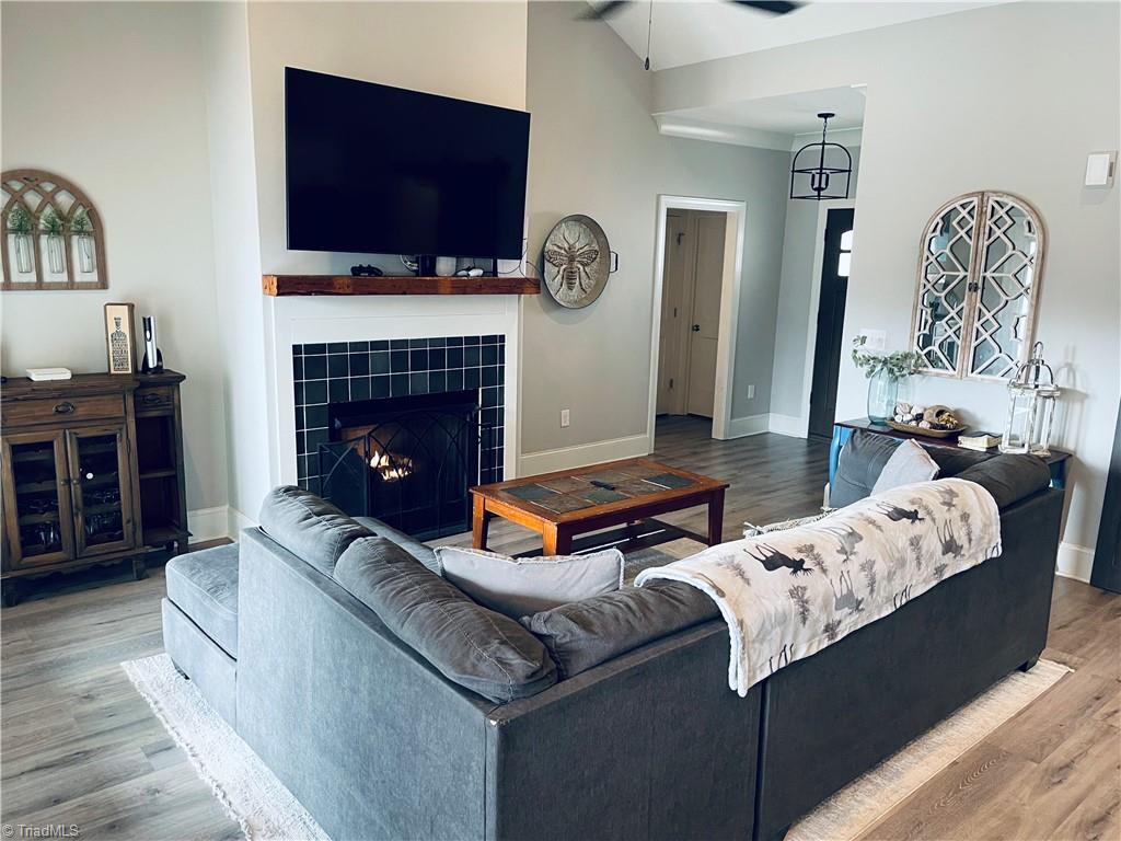 8805 Colgate Road Stokesdale, NC 27357 - Photo 33 of 34 Great room with open floor plan, gas logs, vinyl plank flooring. Great for entertaining and opens to the covered back deck that looks over the large fenced in back yard with garden boxes and a cute chicken house.