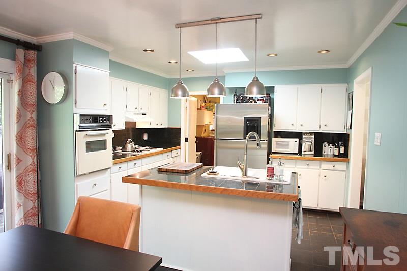 809 Currituck Drive Raleigh, NC 27609 - Photo 3 of 14 a kitchen with stainless steel appliances kitchen island granite countertop a refrigerator a stove and a sink with wooden floor