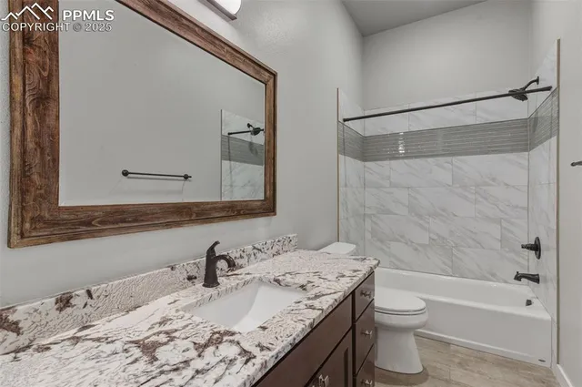 a bathroom with a granite countertop sink a toilet and shower