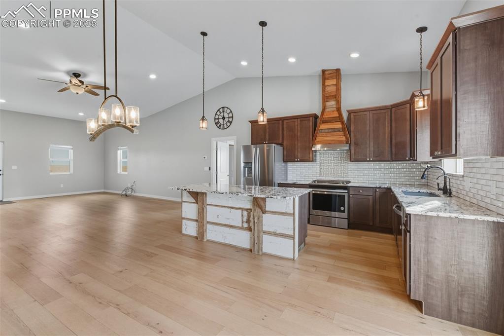 16750 Rabbit Track Trail Colorado Springs, CO 80930 - Photo 9 of 50 Kitchen featuring light stone countertops, hanging light fixtures, appliances with stainless steel finishes, custom exhaust hood, and recessed lighting