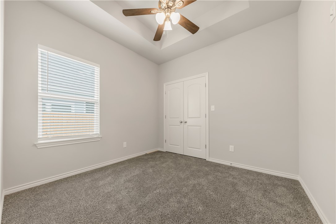 1801 Pin Oak Street Bryan, TX 77803 - Photo 14 of 17 an empty room with a chandelier fan and windows