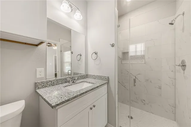 a bathroom with a granite countertop sink a mirror and a shower