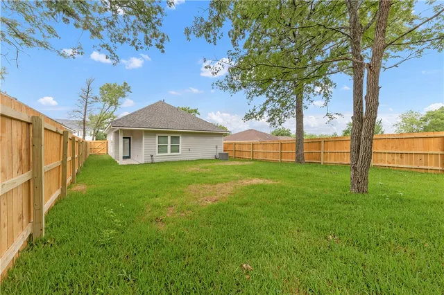 a view of an house with backyard and a tree