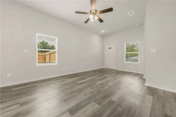a view of an empty room with a window and wooden floor