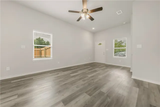 a view of an empty room with a window and wooden floor