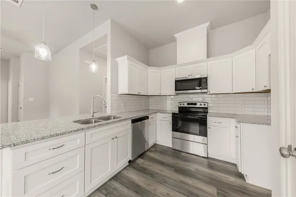 a kitchen with granite countertop white cabinets white stainless steel appliances and a sink