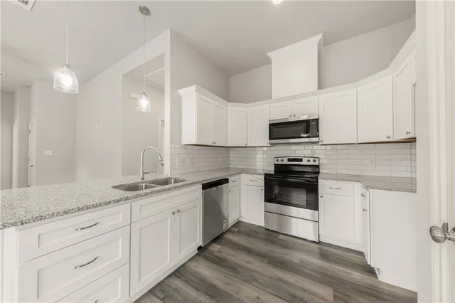 a kitchen with granite countertop white cabinets white stainless steel appliances and a sink