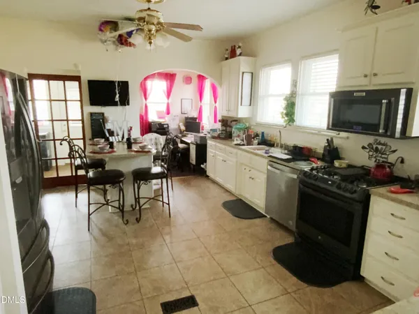a kitchen with stainless steel appliances granite countertop a stove top oven a sink dishwasher and a fireplace with wooden floor