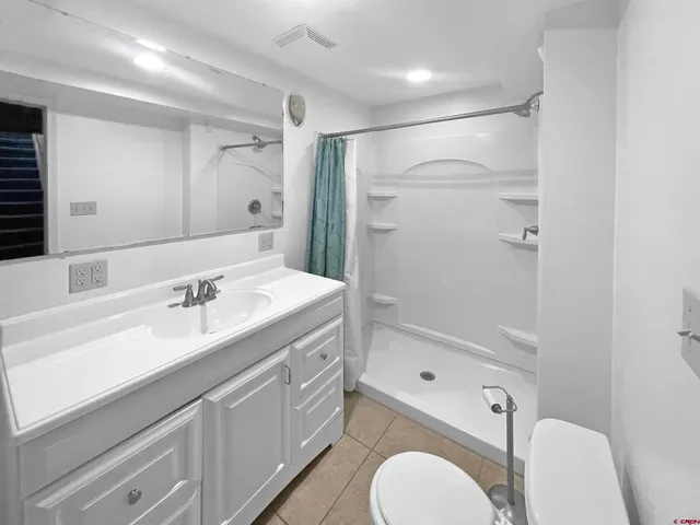 a bathroom with a sink a toilet a mirror and shower