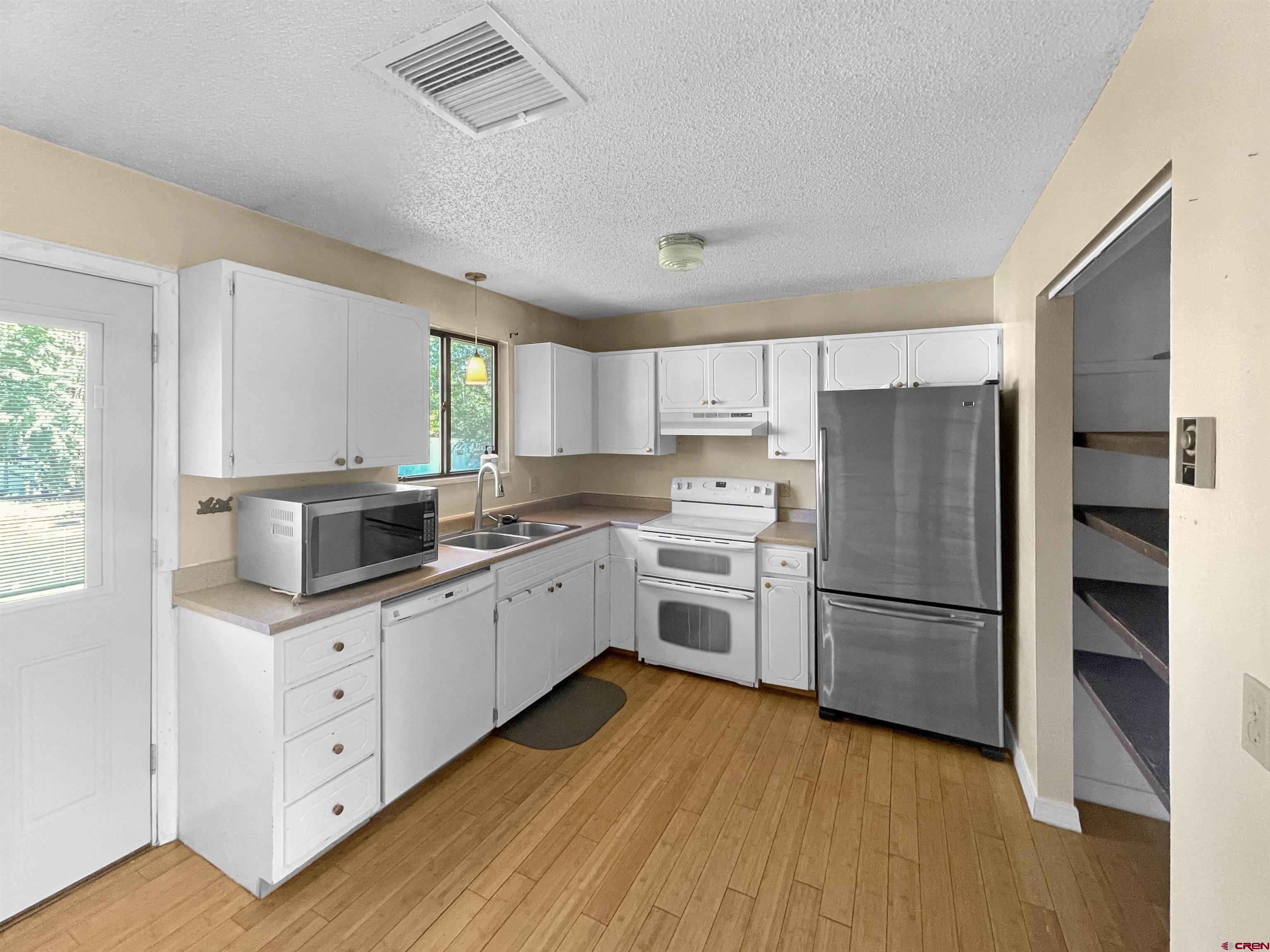 16 West 10th Street Cortez, CO 81321 - Photo 6 of 18 a kitchen with white cabinets and stainless steel appliances