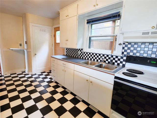 a kitchen with a checkered floor and white cabinets