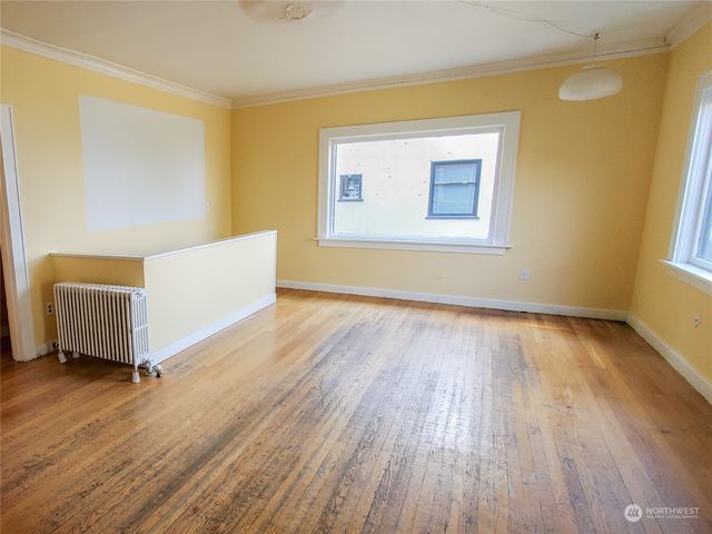 a view of an empty room with wooden floor and a window