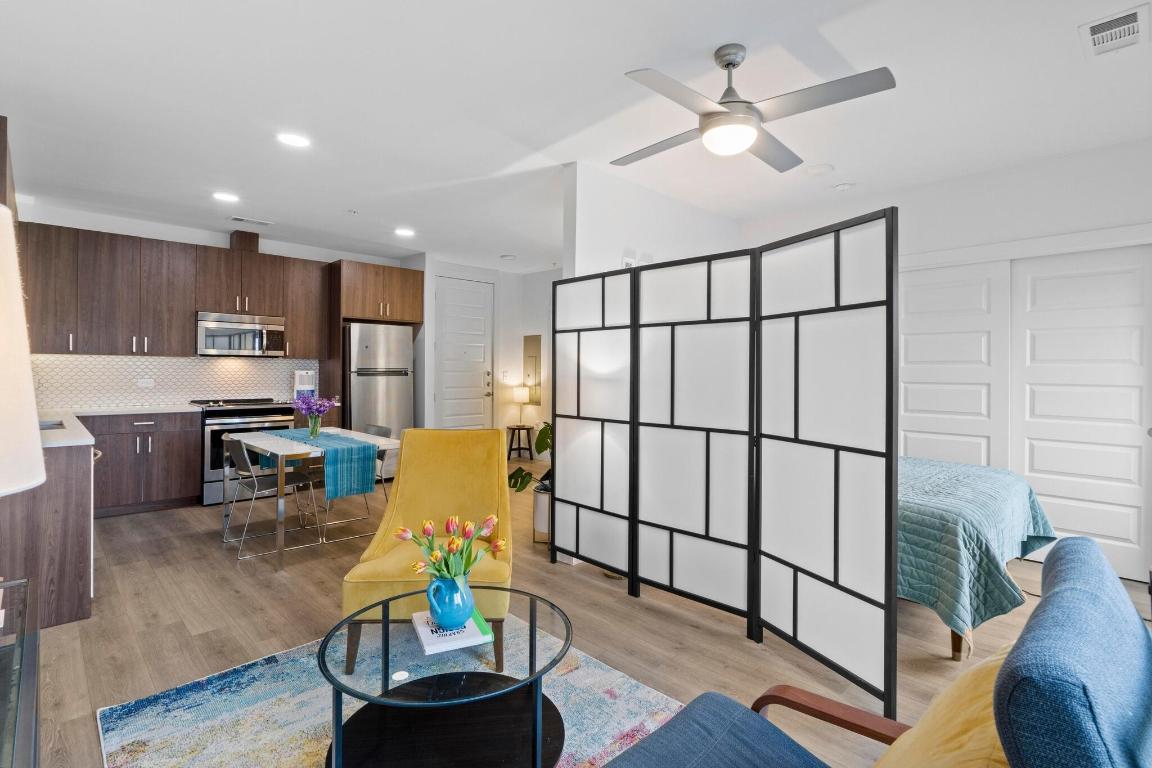 2213 Poquito Street, Unit 319 Austin, TX 78722 - Photo 11 of 22 a living room with furniture appliances and a dining table with wooden floor