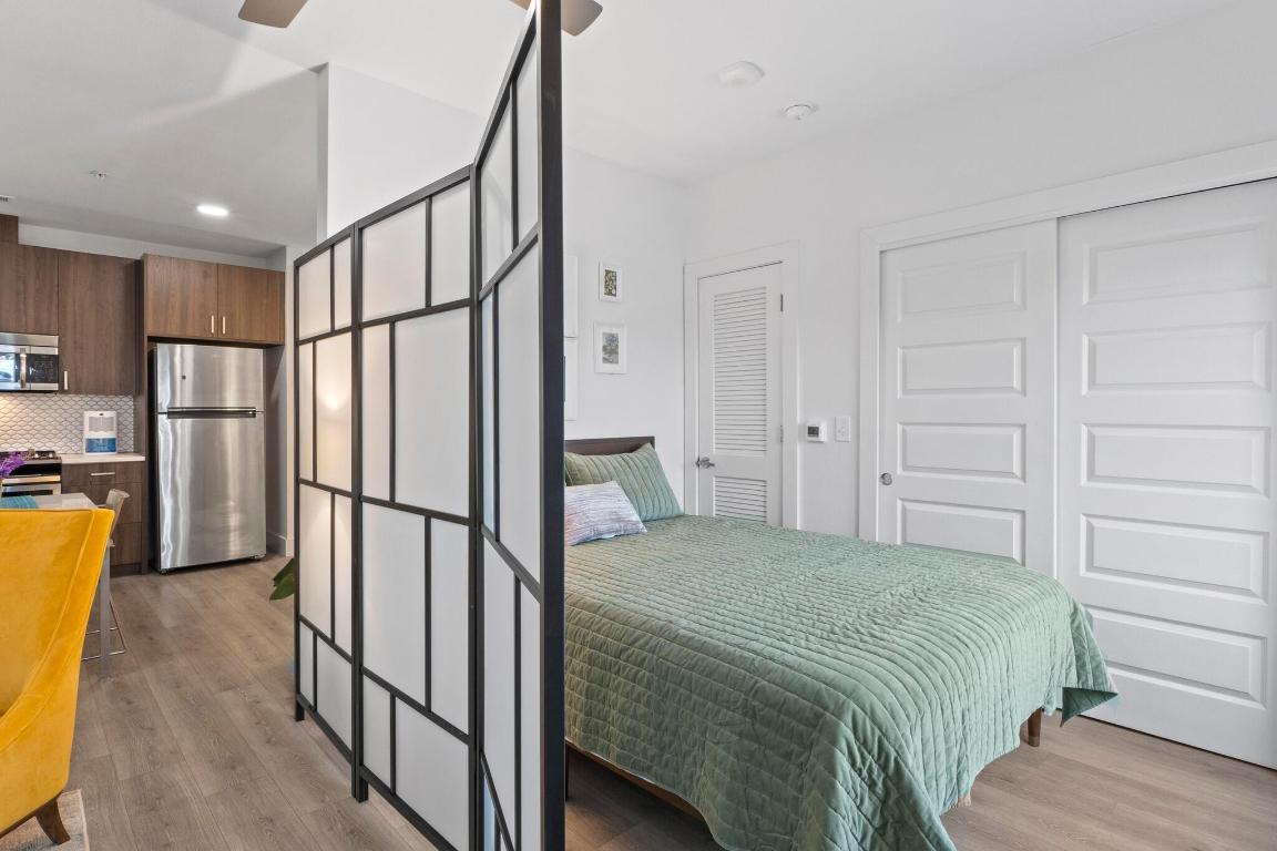 2213 Poquito Street, Unit 319 Austin, TX 78722 - Photo 14 of 22 a bedroom with a bed a mirror on the wall and a shower