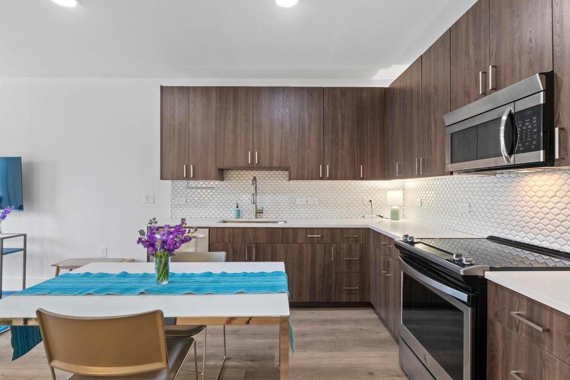 2213 Poquito Street, Unit 319 Austin, TX 78722 - Photo 5 of 22 a kitchen with stainless steel appliances granite countertop a stove top oven microwave and cabinets